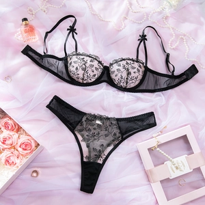 Detailed embroidery on a black lace bra and thong set with silk background