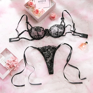 Dettaglio del ricamo rosa nera sul reggiseno in pizzo e perizoma con nastri laterali