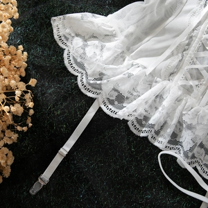 Close-up of white lace lingerie set featuring adjustable garter straps and metal clips