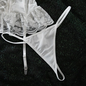 Detail of white lace lingerie set with mesh fabric and floral textures on black background