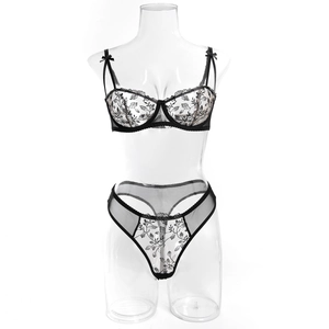 Detail of sheer black lace bra and thong set with white floral embroidery and bow
