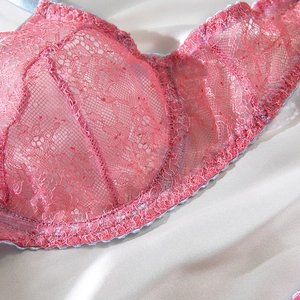 Macro detail of dark pink lace bra with light blue trim and floral pattern texture