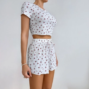 Dettaglio del tessuto a nido d'ape bianco con stampa ciliegie rosse su pantaloncini e top