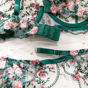 Macro detail of dark green floral embroidery on sheer mesh with hook-and-eye closure