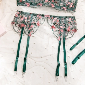Close-up of green floral embroidery on mesh garter belt with pink flowers and pearls