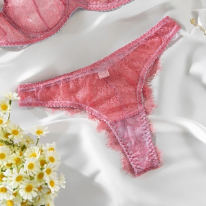 Close-up of pink lace lingerie set with eyelash trim on white silk fabric background