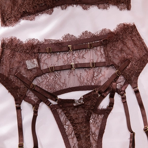 Close-up of deep brown floral eyelash lace lingerie with gold metal buckles and silk background