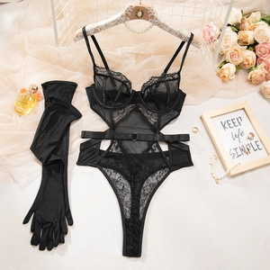 Detailed view of black lace bodysuit with sheer tulle gloves on a decorative background