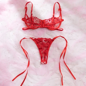 Dettaglio piatto di lingerie rossa con ricamo a rose e perizoma con lacci in raso e perle