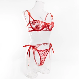 Dettaglio del reggiseno in pizzo rosso con ricamo di rose e fiocco su manichino chiaro