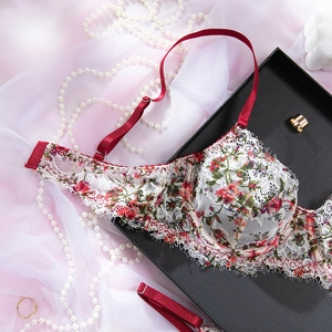 Détail de broderie florale sur soutien-gorge en maille blanche avec bretelles rouges et dentelle