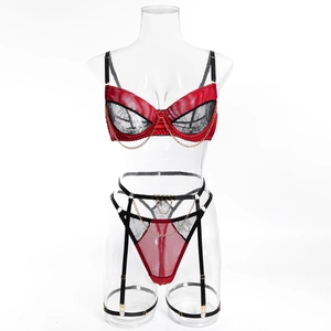 Detail of red satin and black lace lingerie set with gold chain and garter belt