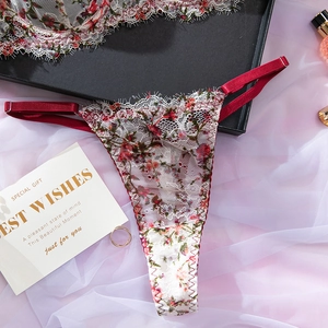 Vue détaillée d'un string en dentelle blanche avec broderies rouges dans une boîte cadeau