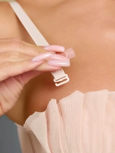 Détail macro de la bretelle réglable et du crochet en plastique sur le haut en tulle rose