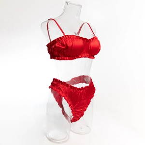 Détail d'un ensemble de lingerie en satin rouge avec bords à volants sur un mannequin transparent