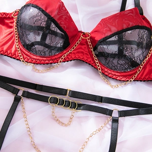 Detail of red satin lingerie with black lace cups and decorative gold chain accents