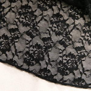 Close-up of black floral lace fabric with detailed rose embroidery and fine mesh texture
