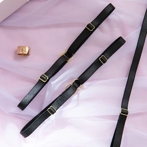 Detail of black elastic lingerie straps with gold metal adjusters and rings on pink mesh