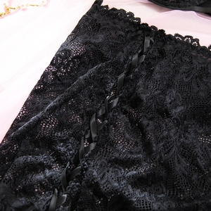 Dettaglio di pizzo nero delicato con allacciatura decorativa in nastro e maglia fine