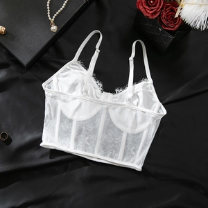 Détail macro d'un corset en dentelle blanche avec bretelles sur fond de soie noire