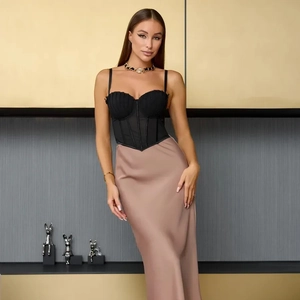 Détail d'un haut corset noir à baleines avec une jupe longue en satin rose poudré