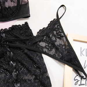Dettaglio di un set di lingerie in pizzo nero con ricami floreali e nastro di raso