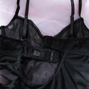 Macro shot of floral daisy embroidery on sheer black mesh bodysuit with adjustable straps