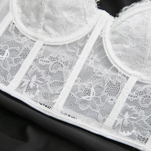 Détail d'un corset en dentelle blanche avec baleines et broderies florales fines