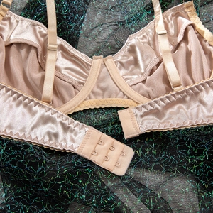 Close-up of adjustable straps and back hook closure on champagne satin underwire bra