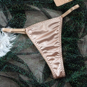 Detail of satin G-string in champagne gold with adjustable metal buckle and wavy edges