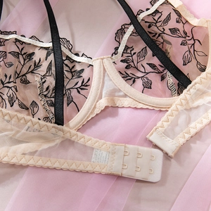 Détail du soutien-gorge en résille beige avec broderie florale noire et agrafes doubles