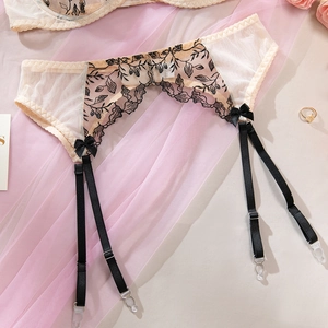 Détail de la broderie florale sur porte-jarretelles en tulle beige et nœuds noirs