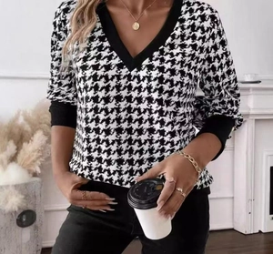 Detail of the V-neckline and black contrast trim on a houndstooth long sleeve top