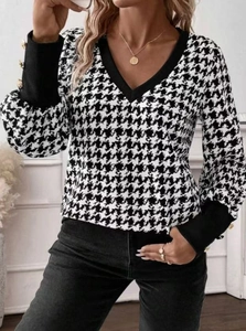Detail of V-neckline and houndstooth pattern with gold buttons on the ribbed cuffs