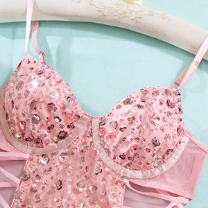 Dettaglio body rosa con paillettes metalliche e allacciatura laterale in tessuto mesh