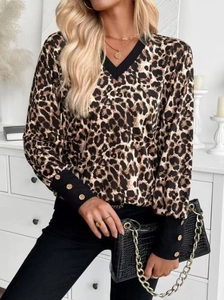 Detail of leopard print blouse featuring contrast V-neck and cuffs with gold buttons