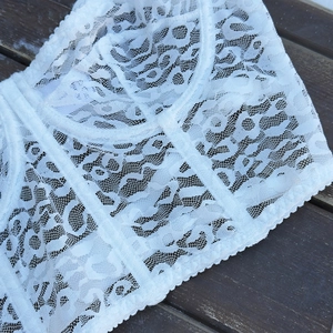 Close-up of white lace corset with boning support and intricate floral patterns