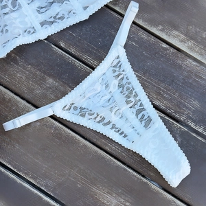 Detailed macro view of white floral lace thong with adjustable elastic side straps
