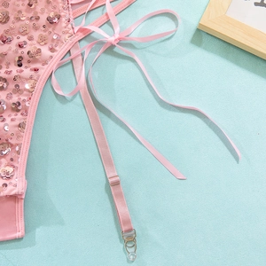 Dettaglio di body in rete rosa con fiori di paillettes e cinghie regolabili