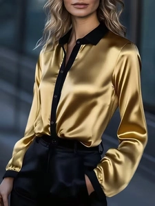 Detailed close-up of golden satin shirt with elegant black contrast collar and cuffs