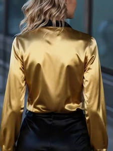 Detail of elegant gold satin shirt with black contrast collar and smooth silk texture