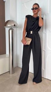 Détail d'une combinaison noire sans manches avec jambe large et boucle de ceinture dorée