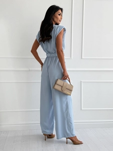 Detail eines hellblauen ärmellosen Jumpsuits mit Schulterpolstern und passendem Gürtel