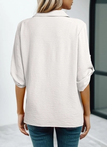 Detail view of white chiffon blouse with rolled buttoned sleeves and textured fabric
