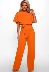 Detail of an orange short sleeve jumpsuit with a belted waist and wide leg trousers