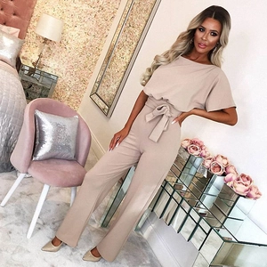Detail of nude short sleeve romper with high waist bow belt and wide leg design