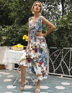Detail of white V-neck floral maxi dress with waist tie in a lush garden setting