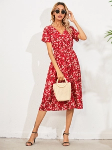 Detailed view of a red floral V-neck dress with white flowers and a matching straw bag
