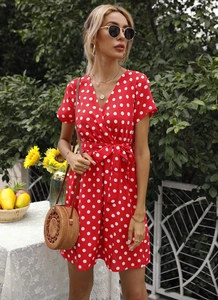Détail d'une robe d'été rouge à pois pour femme avec col en V et ceinture à la taille