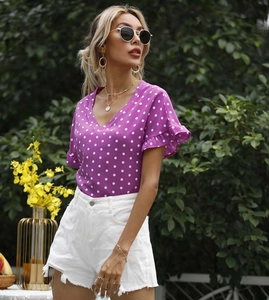 Detail eines violetten Polka-Dot-Oberteils mit V-Ausschnitt und eleganten Rüschenärmeln